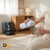 Hình Người Dùng Rót Dung Dịch Ecovacs Vào Ngăn Chứa, Phía Sau Là Robot Và Trạm Sạc. Vị Trí Bổ Sung Và Liều Lượng Cần Thực Hiện Theo Hướng Dẫn Từng Model. Người Dùng Rót Dung Dịch Ecovacs Deebot Từ Chai Vào Ngăn Chứa Tháo Rời.