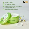 Hình Minh Họa Kamill Classic Mở Nắp, Đặt Cạnh Hoa Cúc Và Vệt Kem Trắng, Kèm Nội Dung Giới Thiệu Bằng Tiếng Đức. Hũ Kem Tay Kamill Classic Mở Nắp Cạnh Hoa Cúc Và Vệt Kem Trắng